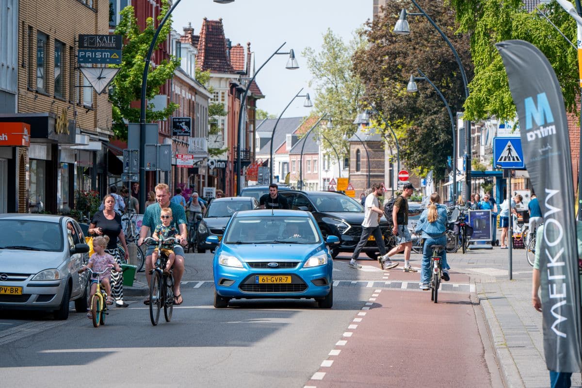 Straat met veel auto's, fietsers en voetgangers